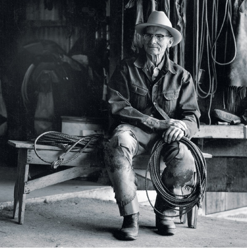 Bill Dorrance — rancher and horseman seated in barn with rawhide rope