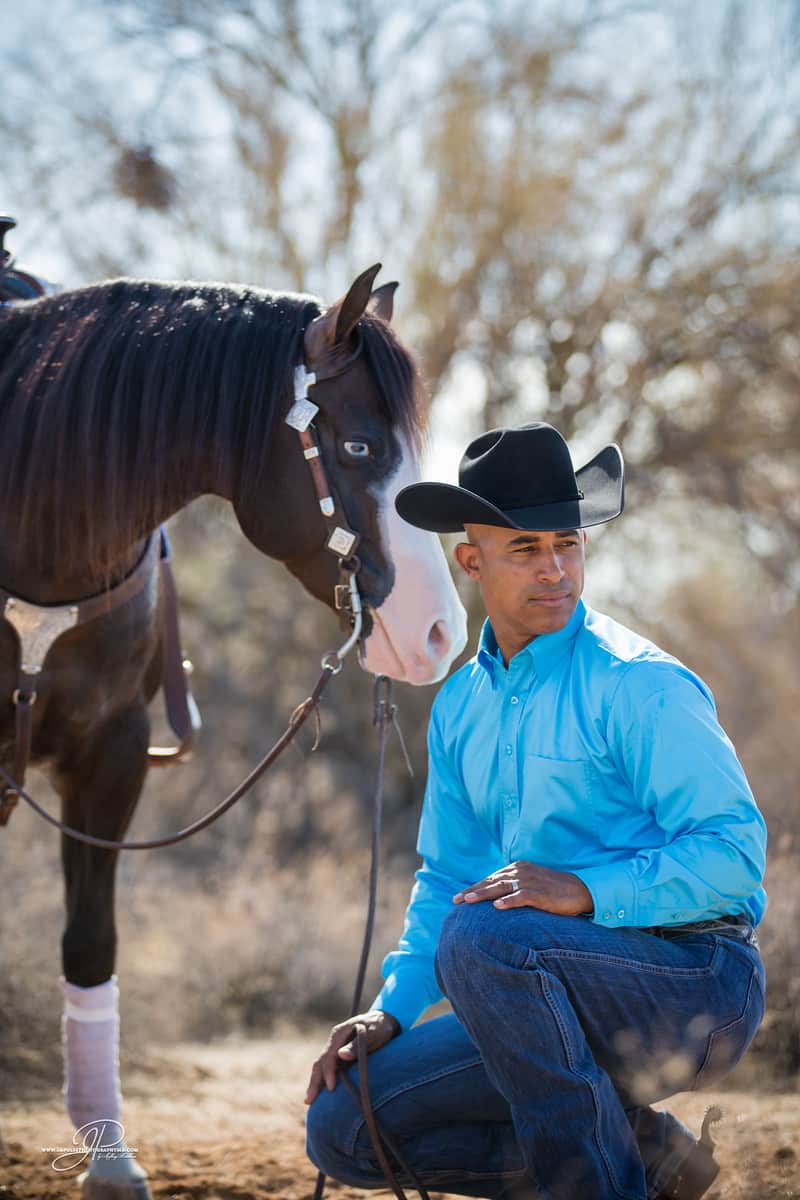 Matt Mills kneeling with a horse in the desert — Arizona
